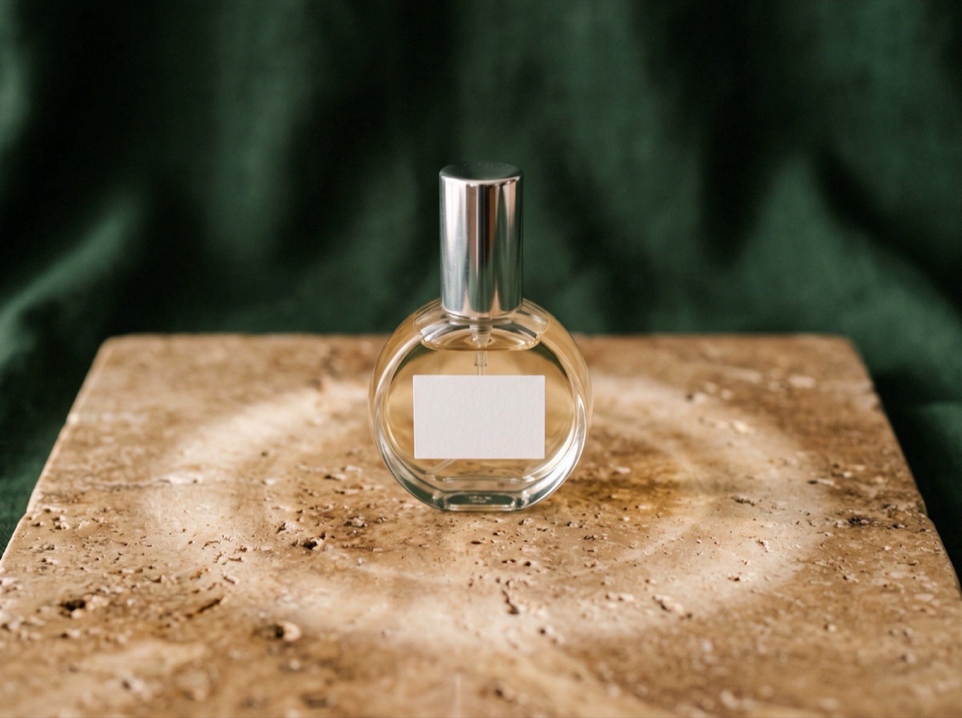 A single 5 ml atomizer on a travertine surface with a soft ring of light around it, suggesting a close scent bubble